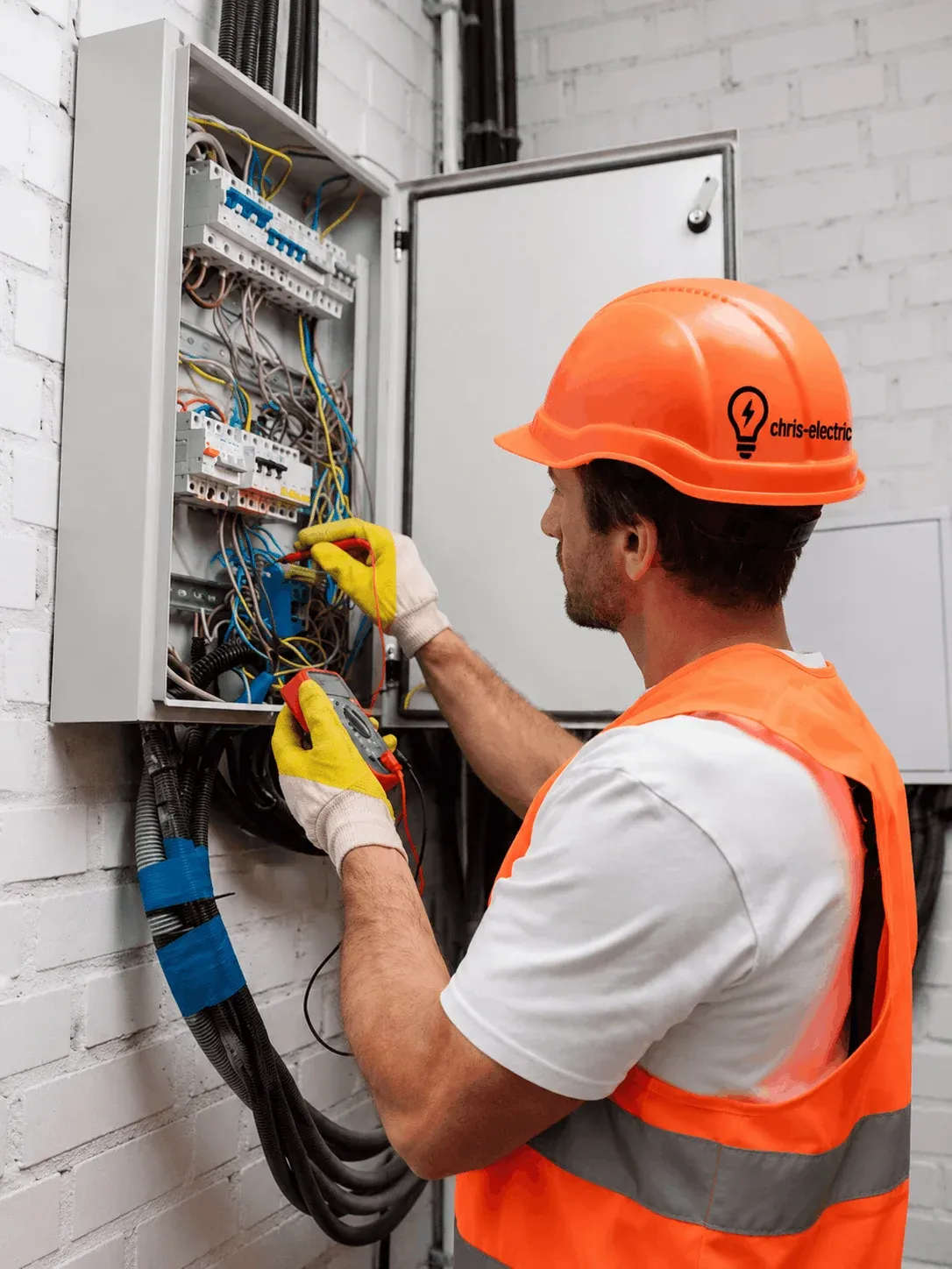 Chris Electric electrician in an orange hard hat testing a breaker panel
